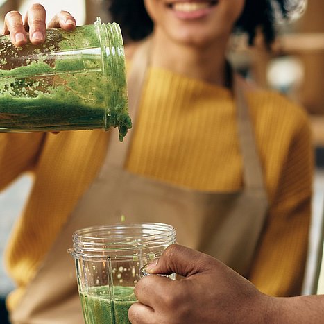 Frau bereitet ein Smoothie-Rezepte in einem Mixer zu.