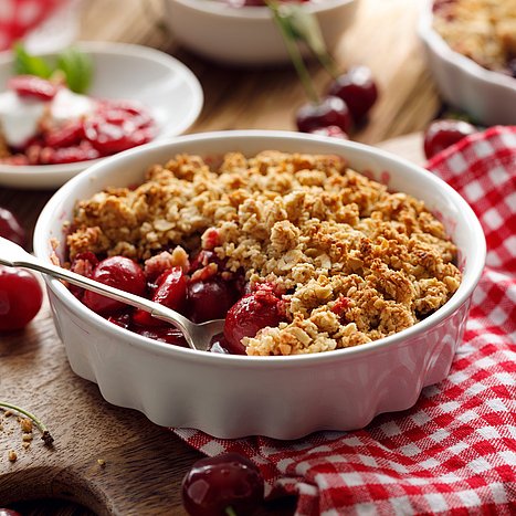 Kirsch-Crumble in einer weißen Auflaufform.