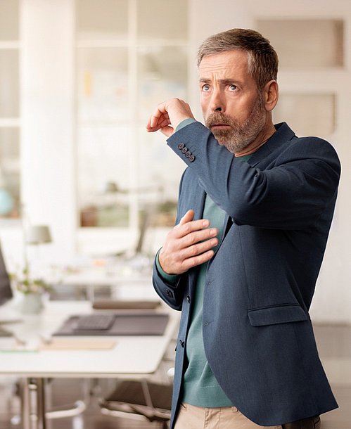 Mann in Büro mit Husten